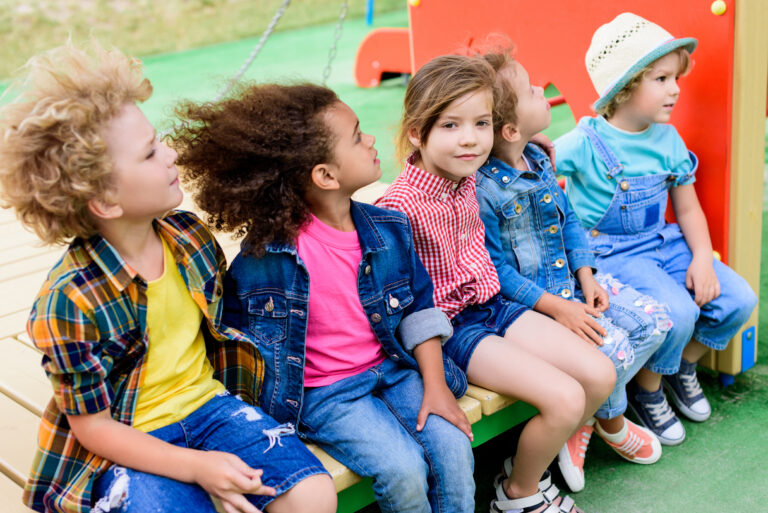 happy multiethnic little children sitting together at playground